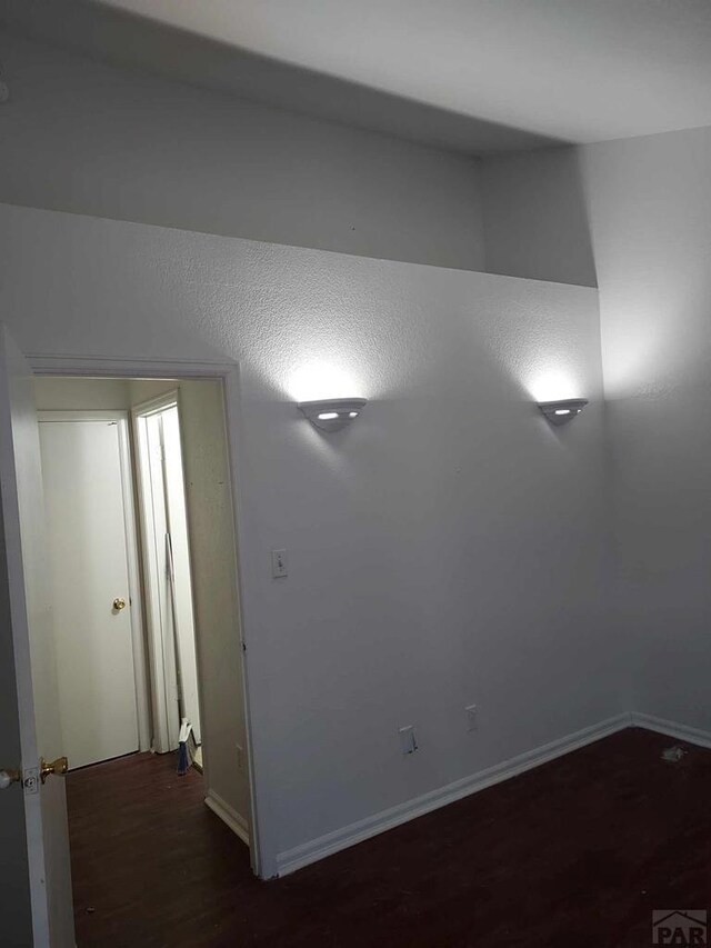 empty room with dark wood-style flooring and baseboards