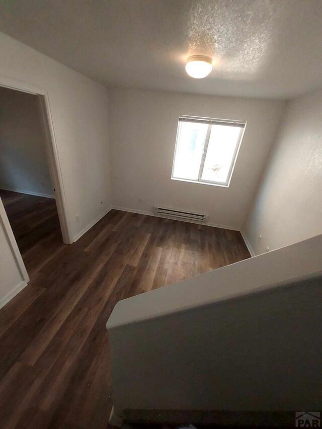 interior space with dark wood-type flooring, baseboards, a textured ceiling, and baseboard heating