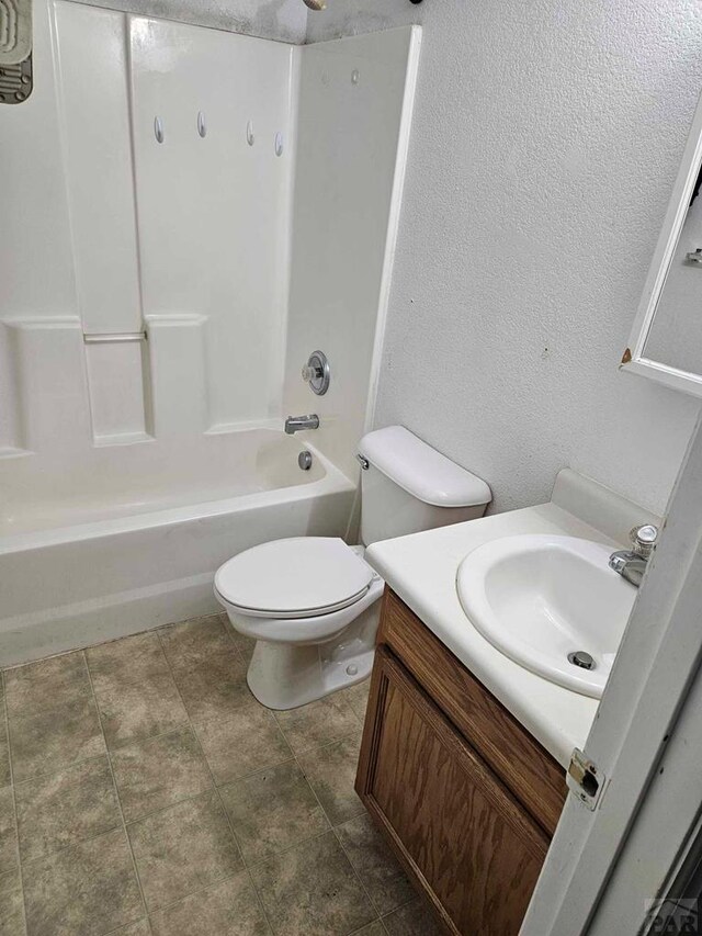 full bathroom featuring toilet, a textured wall, tub / shower combination, and vanity