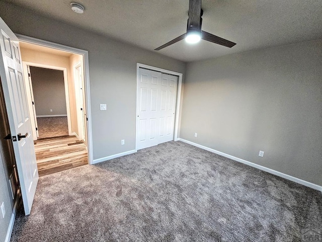 unfurnished bedroom featuring carpet floors, a closet, baseboards, and a ceiling fan