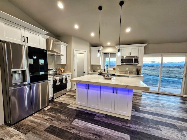 kitchen with a center island, vaulted ceiling, stainless steel appliances, white cabinetry, and pendant lighting