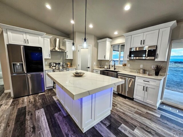 kitchen with white cabinets, wall chimney range hood, stainless steel appliances, and a sink