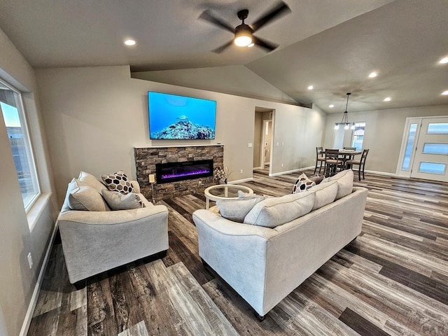 living area featuring baseboards, vaulted ceiling, dark wood-style flooring, and a stone fireplace