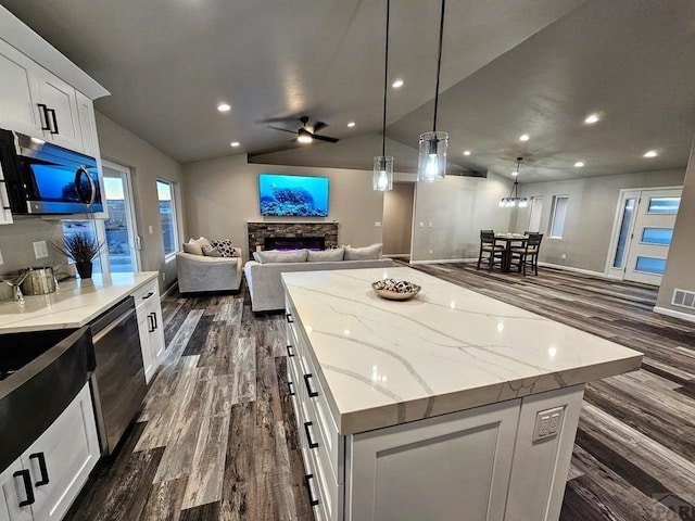 kitchen featuring a spacious island, white cabinetry, black dishwasher, open floor plan, and stainless steel microwave