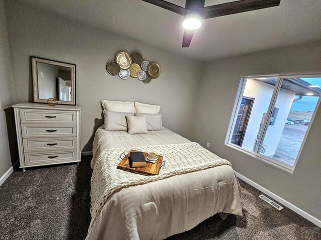 bedroom featuring baseboards, visible vents, dark carpet, and a ceiling fan