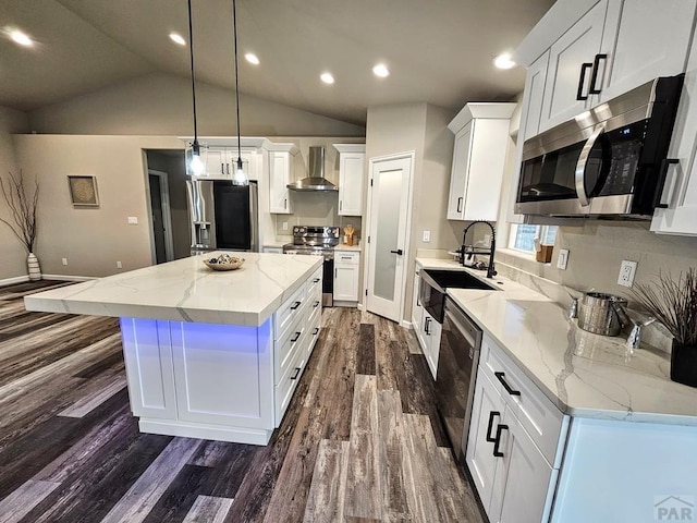 kitchen featuring a sink, a kitchen island, white cabinetry, appliances with stainless steel finishes, and wall chimney exhaust hood