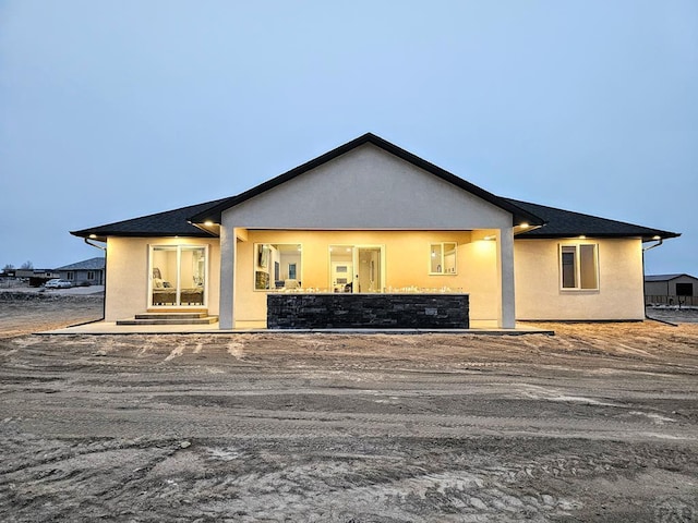 rear view of house featuring stucco siding