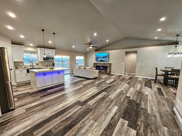 kitchen with white cabinets, a kitchen island, stainless steel microwave, open floor plan, and decorative light fixtures