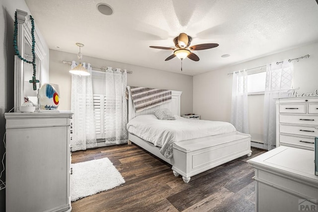67 Macarthur Rd, Pueblo, CO 81001 - bedroom with dark wood-style floors, a baseboard radiator, a ceiling fan, and a textured ceiling