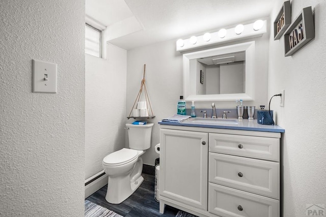 67 Macarthur Rd, Pueblo, CO 81001 - half bathroom with vanity, a textured wall, baseboard heating, and wood finished floors