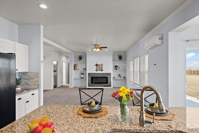 kitchen featuring light stone counters, light carpet, white cabinetry, an AC wall unit, and freestanding refrigerator