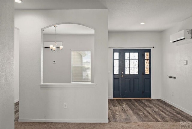 foyer with arched walkways, a chandelier, dark wood-type flooring, baseboards, and a wall mounted AC