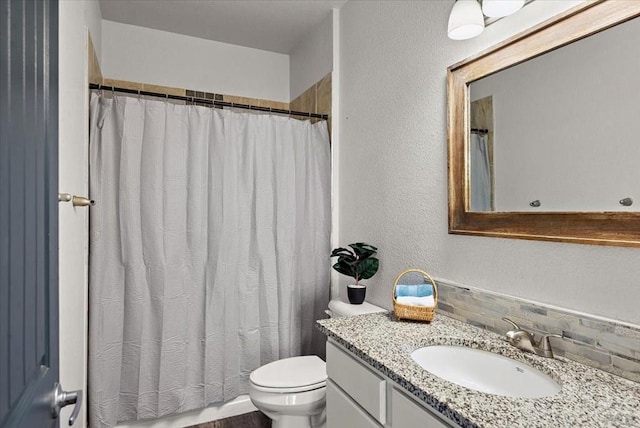 bathroom with a textured wall, vanity, and toilet