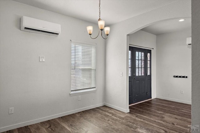 entrance foyer with a wealth of natural light, dark wood-style floors, arched walkways, and an AC wall unit