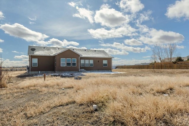 rear view of property with a rural view and fence