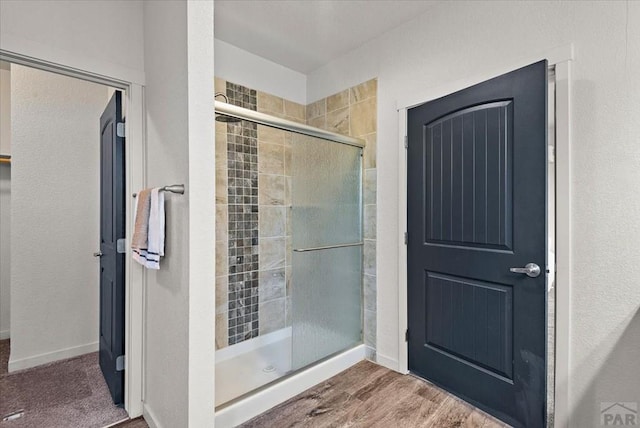 full bathroom with a shower stall, baseboards, and wood finished floors