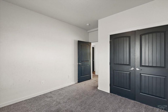 unfurnished bedroom featuring dark colored carpet, a closet, and baseboards