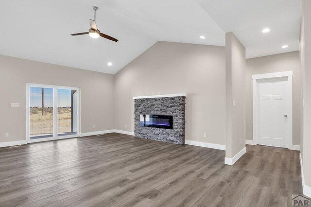 unfurnished living room featuring baseboards, lofted ceiling, ceiling fan, wood finished floors, and a fireplace