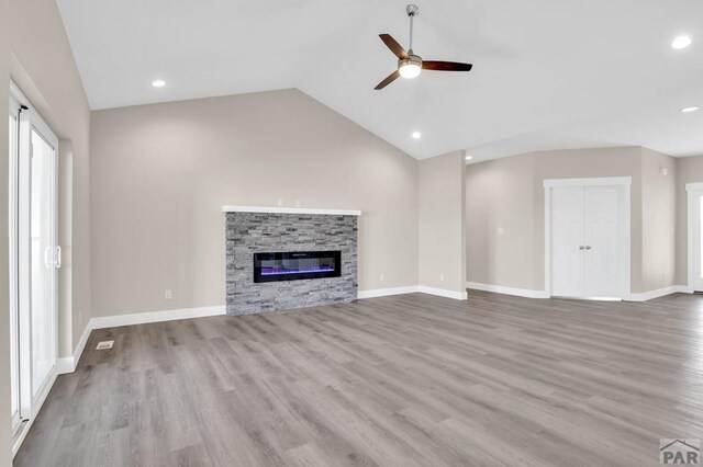 unfurnished living room featuring light wood-type flooring, a fireplace, lofted ceiling, and baseboards