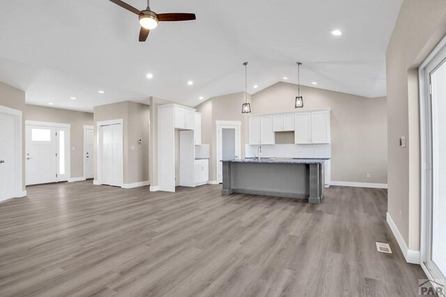 kitchen with open floor plan, a center island with sink, and white cabinetry