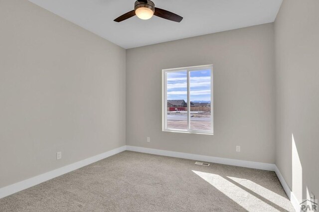 spare room featuring baseboards, ceiling fan, visible vents, and light colored carpet