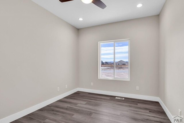 spare room featuring ceiling fan, dark wood-style flooring, visible vents, and baseboards