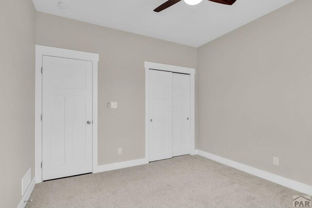 unfurnished bedroom featuring a ceiling fan, baseboards, a closet, and light colored carpet