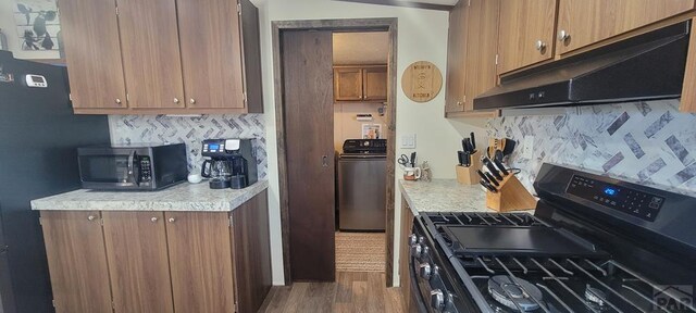 kitchen with black appliances, brown cabinetry, light countertops, and under cabinet range hood