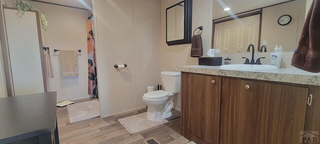 full bathroom with toilet, wood finished floors, and vanity