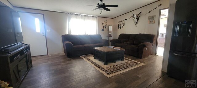 living area featuring dark wood-style floors, ornamental molding, and a ceiling fan