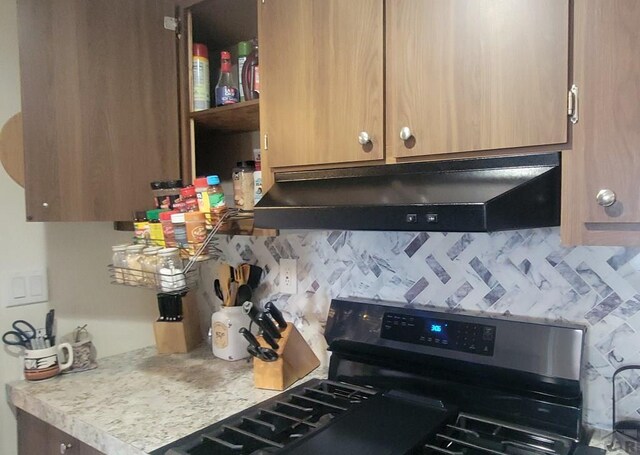 kitchen featuring under cabinet range hood, decorative backsplash, range, and light countertops