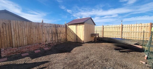 view of yard with an outbuilding, a fenced backyard, and a shed