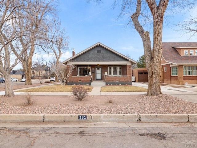 bungalow-style home featuring an attached garage, brick siding, driveway, crawl space, and a chimney