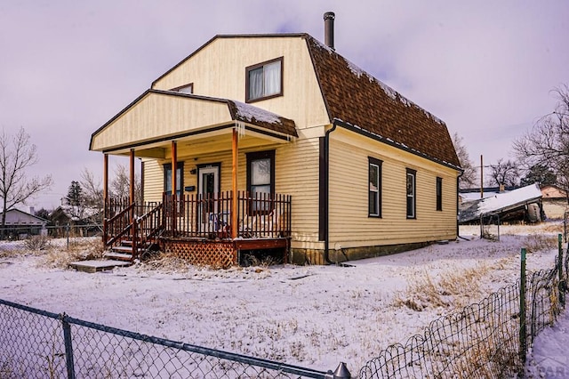 view of front of house featuring a shingled roof, fence, a porch, and a gambrel roof