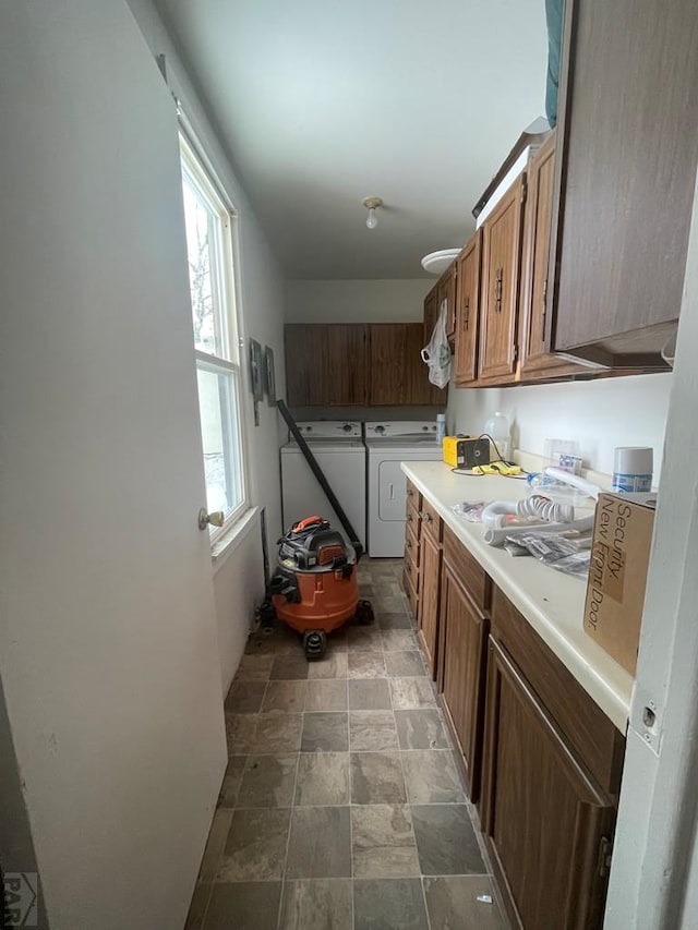 kitchen with light countertops, stone finish floor, washing machine and clothes dryer, and brown cabinets