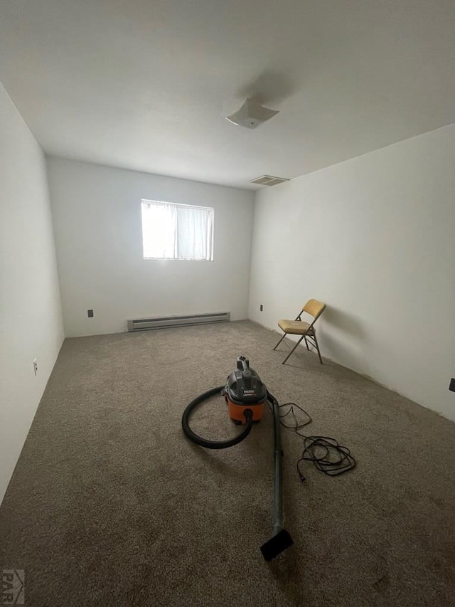 interior space featuring a baseboard heating unit, visible vents, and carpet flooring