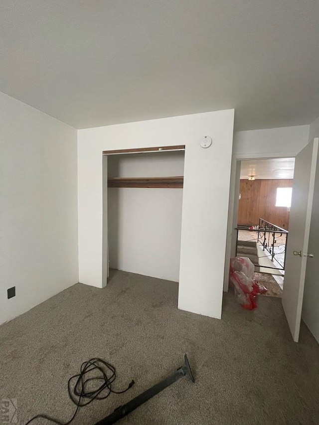 unfurnished bedroom with dark colored carpet and a closet