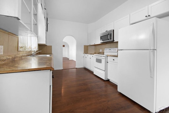 1142 Elm St, Pueblo, CO 81004 - kitchen featuring white appliances, arched walkways, backsplash, dark wood-style floors, and white cabinets