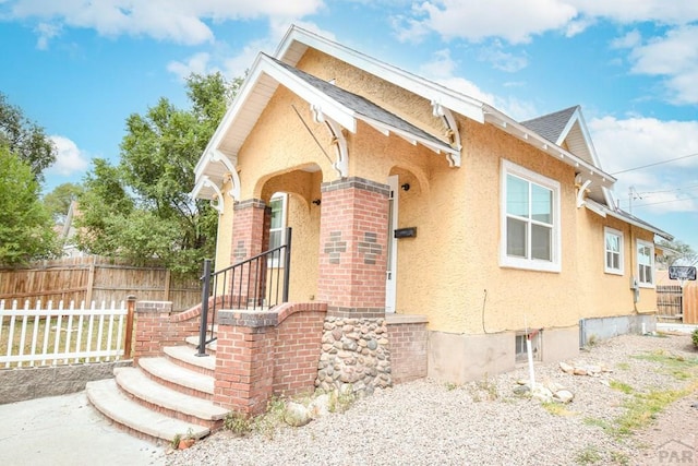 1142 Elm St, Pueblo, CO 81004 - view of front facade featuring stucco siding, a shingled roof, and brick siding