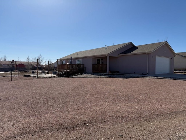 view of front of home featuring a garage, fence, and stucco siding