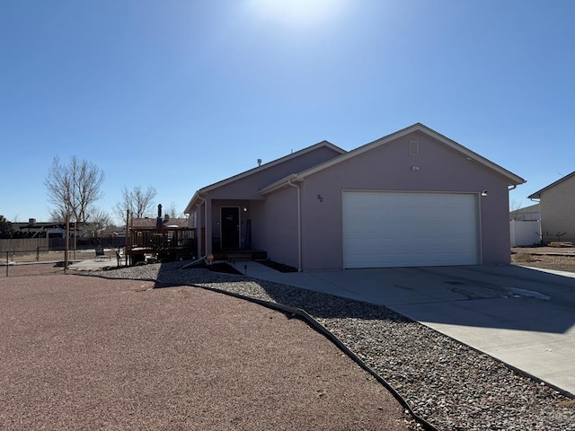 view of front of property with a garage, concrete driveway, fence, and stucco siding