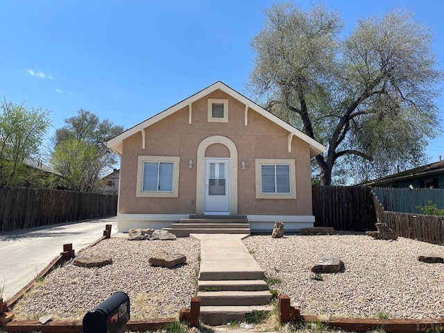 bungalow featuring fence and stucco siding