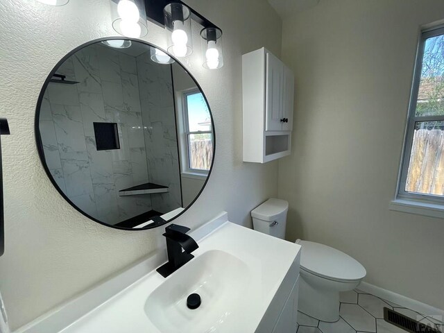 full bath featuring toilet, vanity, visible vents, and baseboards