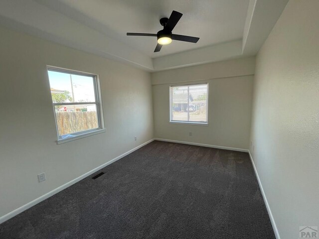 spare room featuring a wealth of natural light, a raised ceiling, visible vents, and baseboards