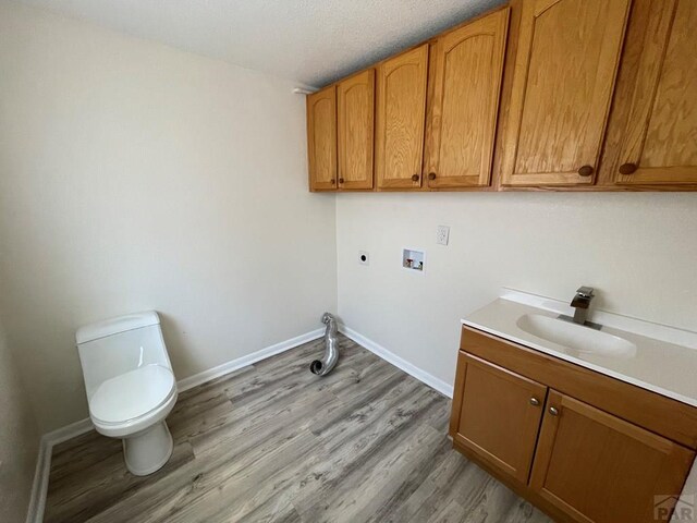 clothes washing area with light wood-style flooring, laundry area, a sink, baseboards, and electric dryer hookup