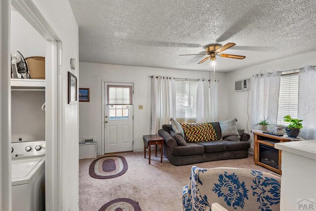 carpeted living room featuring washer / clothes dryer, a wall mounted air conditioner, ceiling fan, and a textured ceiling