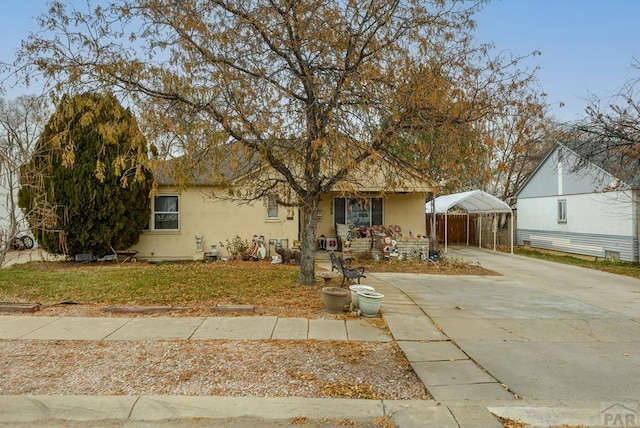 view of front of house featuring concrete driveway, a front yard, a carport, and stucco siding