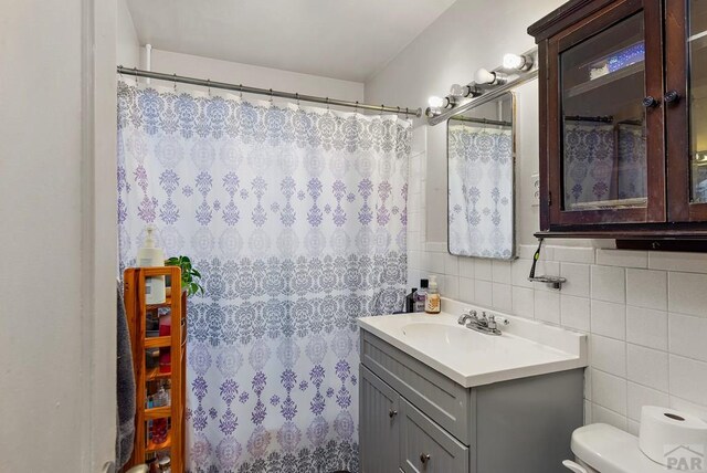 full bathroom featuring toilet, tile walls, and vanity