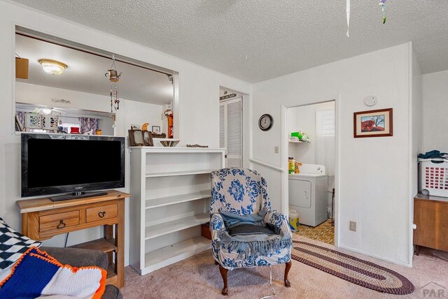 living area with light carpet, washer / clothes dryer, and a textured ceiling