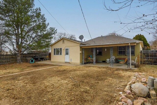 rear view of property featuring a fenced backyard, a patio, and stucco siding